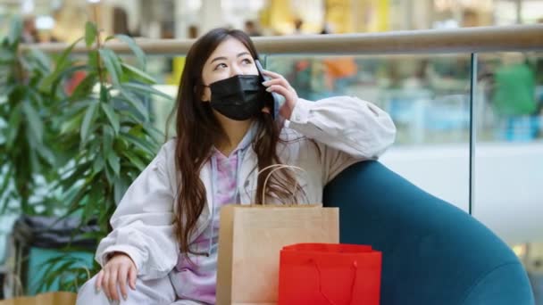 Mulher em máscara conversando no telefone no centro comercial — Vídeo de Stock