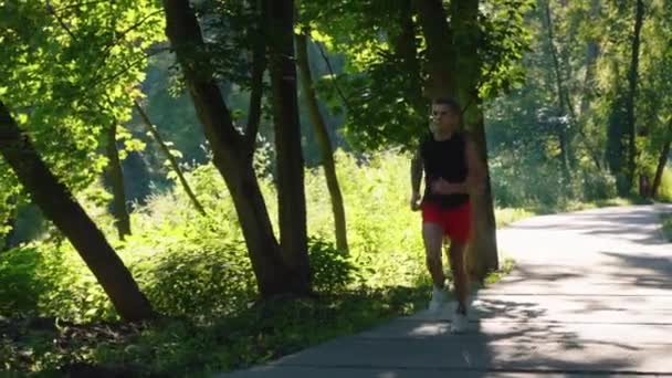 Zeitlupenläufer im sonnenbeschienenen Park — Stockvideo