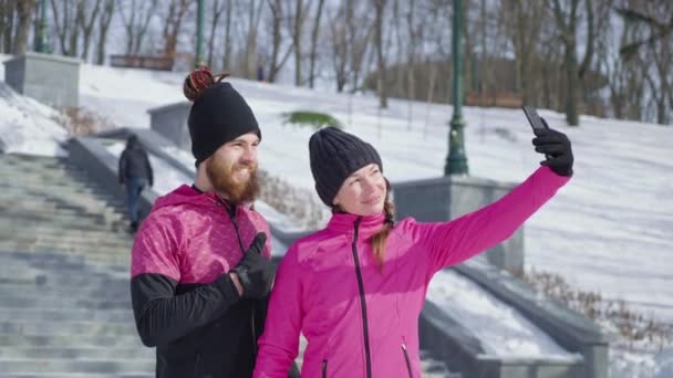 Счастливая пара делает селфи после пробежки в зимнем парке — стоковое видео
