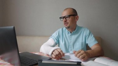 Kolu kırık bir adam online iş görüşmesi yapıyor.