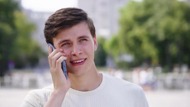 Веселый мужчина разговаривает по телефону в городском парке — стоковое видео