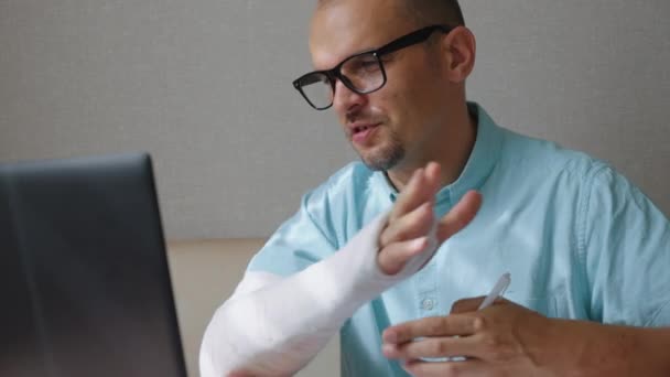 Бизнесмен, работающий из дома после травмы руки — стоковое видео