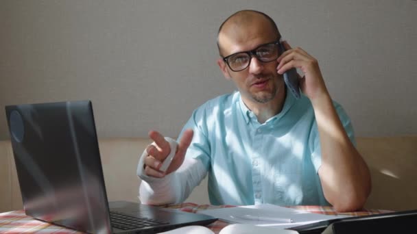 Affärsman med bruten arm som förhandlar i telefon — Stockvideo