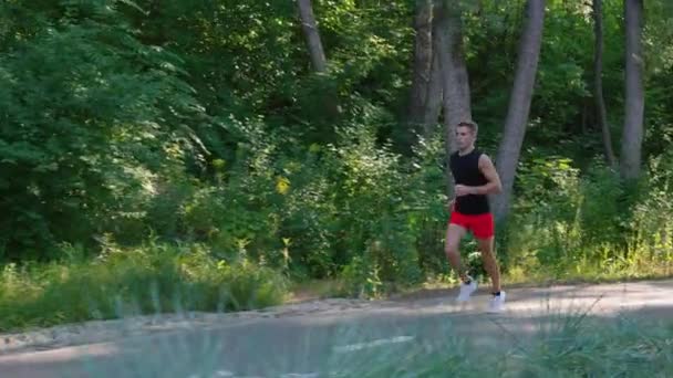 Атлетик бегает в парке в замедленной съемке — стоковое видео