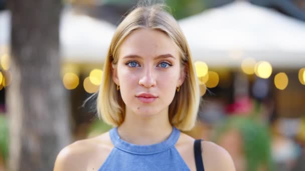 Блондинка с голубыми глазами позирует перед уличным кафе — стоковое видео
