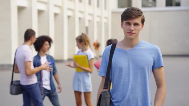 Портрет студента, стоящего возле здания университета — стоковое видео
