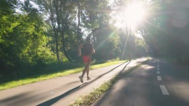 Adam sabah güneşinde parkta koşuyor.