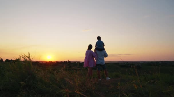 Milující rodina sleduje západ slunce na vrcholu kopce — Stock video