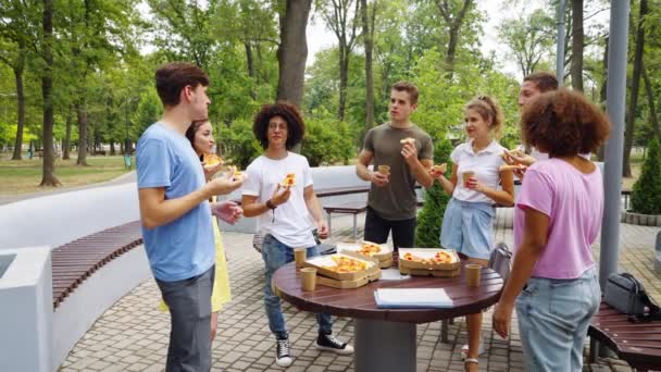 Amigos comiendo pizza en el parque después de clases — Vídeo de stock