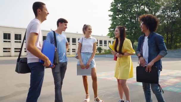 Wieloetniczni studenci dobrze się bawią rozmawiając w pobliżu uczelni — Wideo stockowe