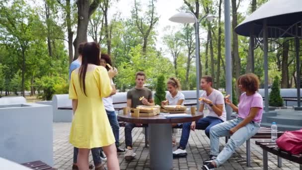Studenci jedzący pizzę na obiad w parku — Wideo stockowe