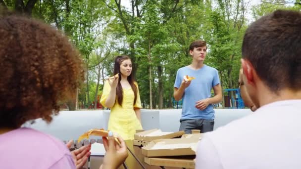 Barátok gyülekeznek pizzázni a parkban — Stock videók