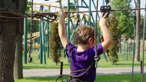 Junge bewegt Sicherheitsgurt auf Seilbahn in Freizeitpark — Stockvideo