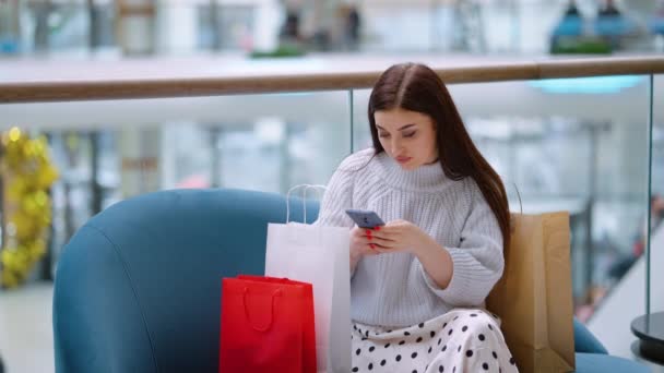 Mujer sentada en el centro comercial y mensaje de texto — Vídeo de stock