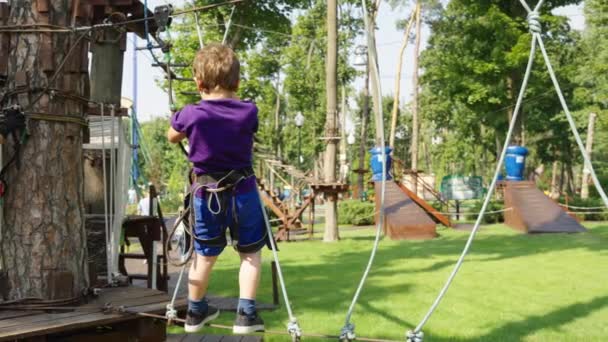Kleiner Junge tritt auf Seilbahn in Freizeitpark — Stockvideo