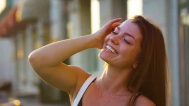 Neşeli kadın gün batımında saçlarına dokunuyor.