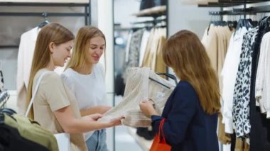 Moda mağazasında birlikte hırka seçen kadın arkadaşlar.