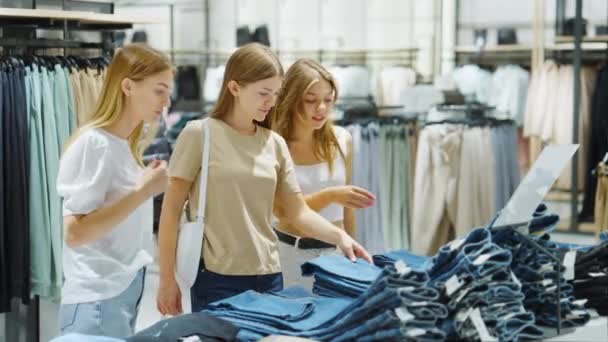 Друзья выбирают джинсы в магазине одежды — стоковое видео
