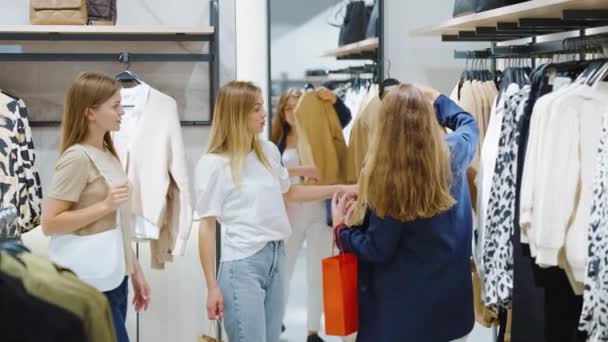 Amigos do sexo feminino discutindo casaco de lã enquanto faz compras na loja de roupas — Vídeo de Stock