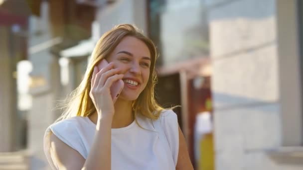 Blondynka rozmawiająca szczęśliwie przez telefon w mieście — Wideo stockowe