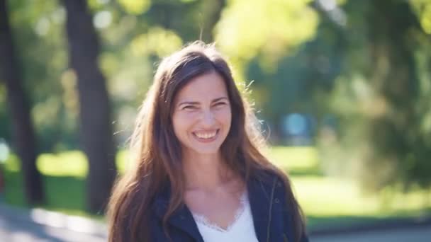 Счастливая женщина смеется в парке в солнечную погоду — стоковое видео