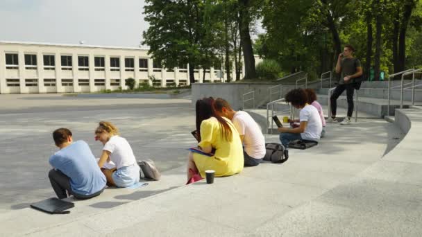 Studenti relaxují po vyučování na schodech — Stock video