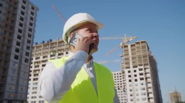 İnşaat müfettişi inşaat alanında telefonla konuşuyor.