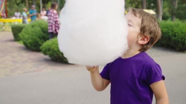 Malé dítě kousání nadýchané cukrové nitě v zábavním parku — Stock video