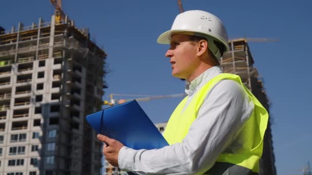Inspector en el sitio de construcción haciendo notas en papel — Vídeos de Stock