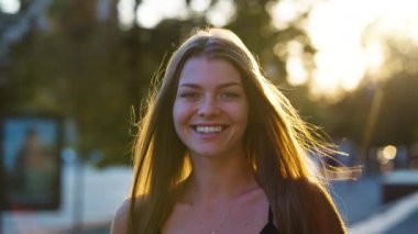 Şehirde gün batımına karşı gülümseyen kadın