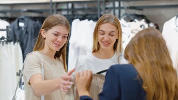 Amigas eligiendo ropa juntas en el centro comercial — Vídeos de Stock