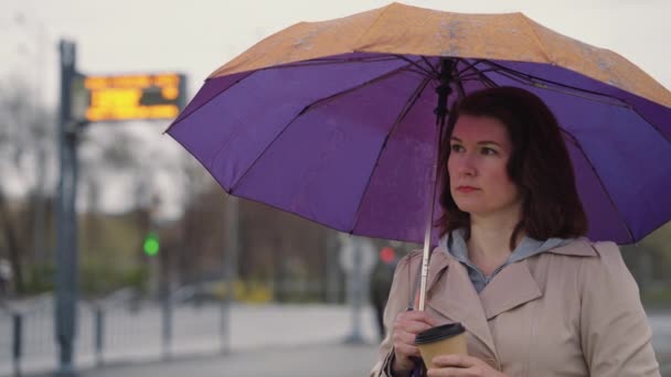 Droevige vrouw onder paraplu koffie drinken — Stockvideo