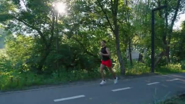 Mouvement lent fit homme jogging dans un parc ensoleillé — Video