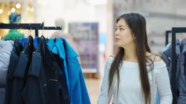 Asyalı kadınlar giyim mağazasında yürüyor