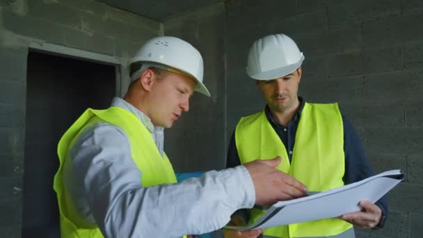 Team av ingenjörer diskuterar ritning på byggarbetsplatsen — Stockvideo