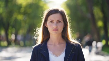 Güneşli bir günde parkta gülümseyen bir kadın.