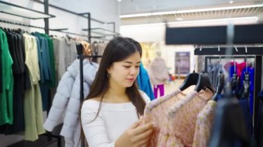 Moda mağazasında elbise seçen Asyalı kadın.