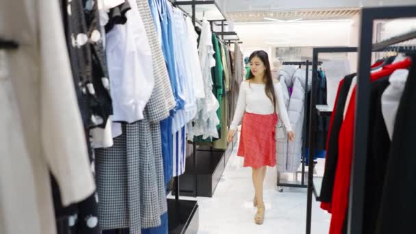 Азиатка, прогуливающаяся среди проходов в магазине моды — стоковое видео