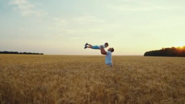 Ağır çekimde baba oğlunu sahada havaya fırlatıyor.