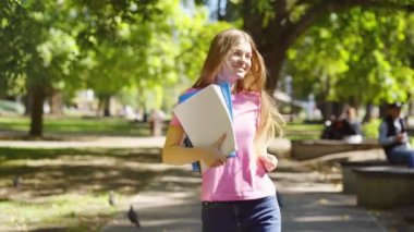 Öğrenci dışarıda kitaplarla dans etmekten mutlu.