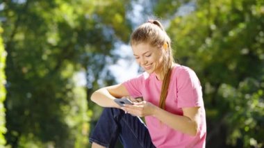 Mesaj atan ve parkta gülen bir kadın.