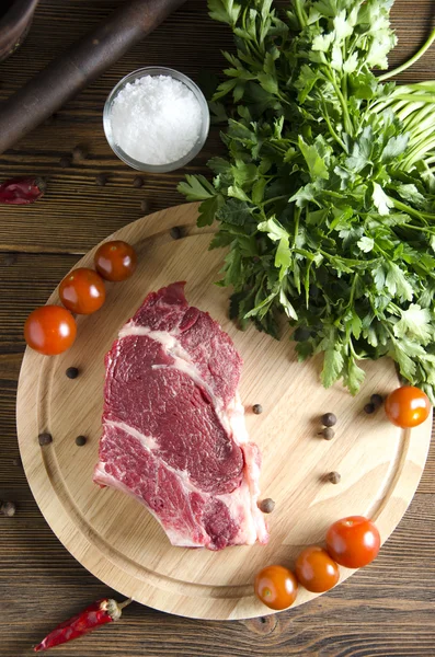 Bistecca di manzo cruda su una tavola di legno su uno sfondo di legno — Foto Stock