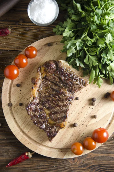Grilled beef steak on wooden board on wooden background — Stock Photo, Image