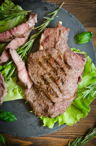 Grilled steak black plate wooden table close up — Stock Photo, Image