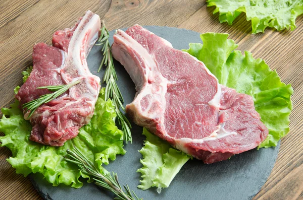 Raw steak black plate wooden table — Stock Photo, Image