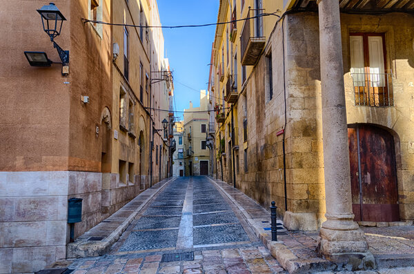 Narrow empty morning street in old part of Tarragona, summer Spain