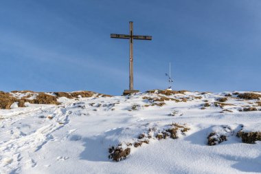 Karlı dağın zirvesinde çaprazlı panorama, güneş yıldızlı ahşap haç, zirveye giden yol, örtülü siluet arka plan, güneşli kış gününde güneşli bir kış günü Rheintal 'den Sntis' e manzaralı paskalya yürüyüşü.