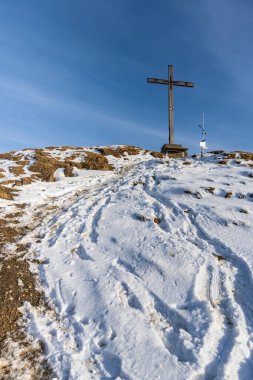 Karlı dağın zirvesinde çaprazlı panorama, güneş yıldızlı ahşap haç, zirveye giden yol, örtülü siluet arka plan, güneşli kış gününde güneşli bir kış günü Rheintal 'den Sntis' e manzaralı paskalya yürüyüşü.