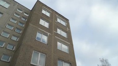 Bulutlu bir arkaplanı olan Sovyet döneminden kalma apartman cephesi