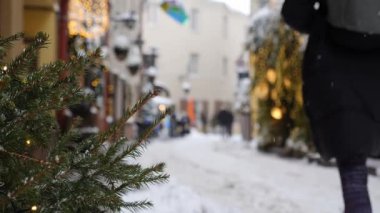 Şehirde kar yağışı, bulanık arka plan, kış tatilleri için sokak dekorasyonu, yayalar, yavaş çekim manzarası.